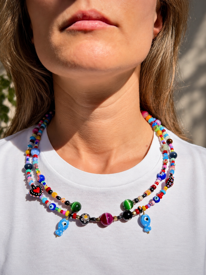 Dos líneas de cuentas multicolores con figuras colgantes azules y elementos redondeados verdes y violetas.